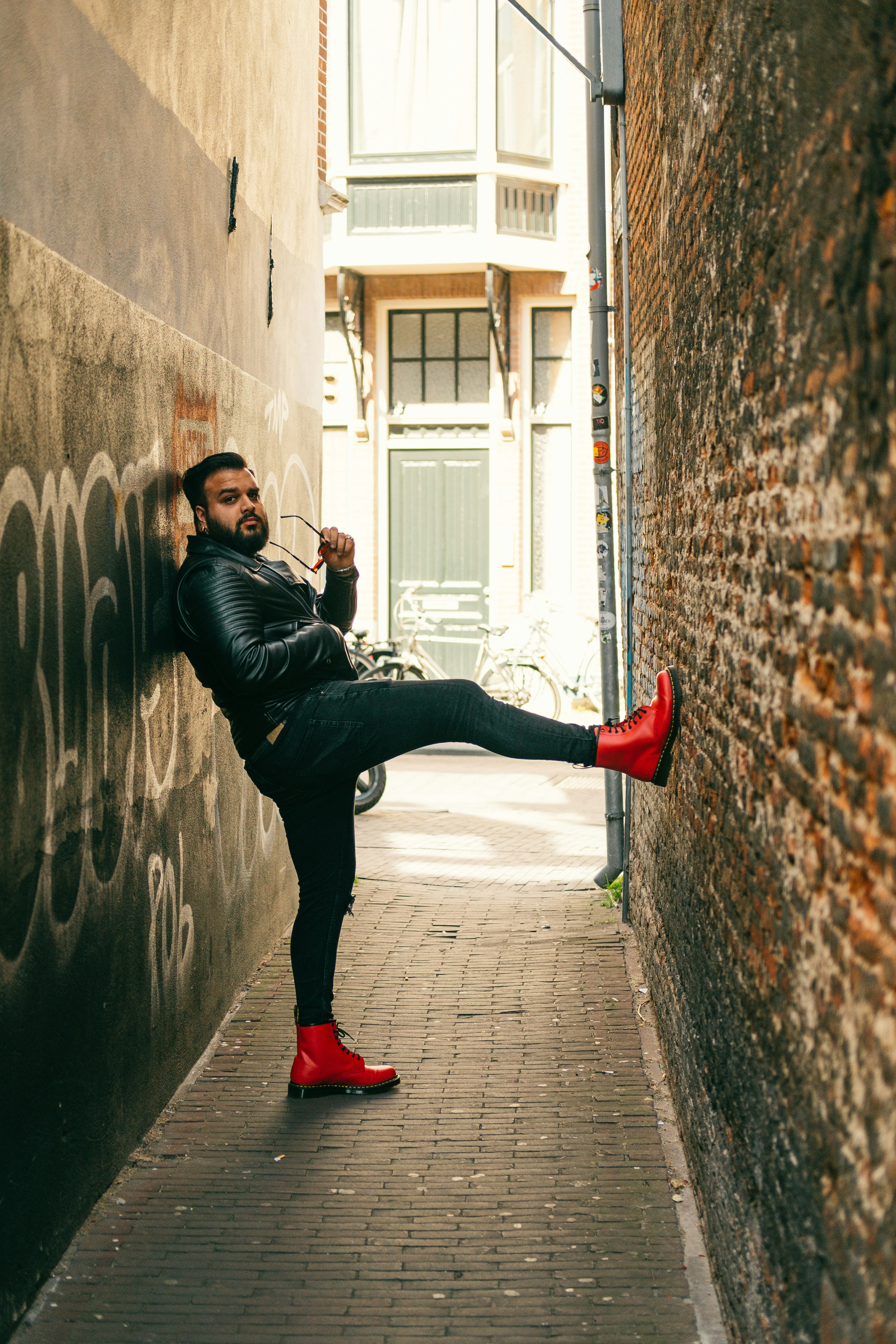 man in black leather jacket and black pants jumping on gray brick wall during daytime